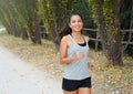 Active sporty young runner woman running in the park. Smiling runner athlete training outdoors Royalty Free Stock Photo