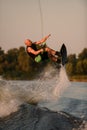 active strong man holds rope and making extreme jump showing trick with wakeboard.