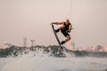 active strong man holds cable and skilfully making extreme jump showing trick on wakeboard.