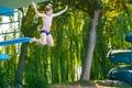 Active teenager boy jumping into an outdoor pool from spring board or 5 meters diving tower learning to dive during Royalty Free Stock Photo