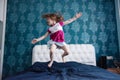 Active toddler girl dancing in bed baby jumping on white and blue bed blur background. what to do in quarantine Royalty Free Stock Photo