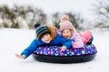 Active toddler girl and school boy sliding together down the hill on snow tube. Happy children, siblings having fun Royalty Free Stock Photo