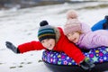 Active toddler girl and school boy sliding together down the hill on snow tube. Happy children, siblings having fun Royalty Free Stock Photo