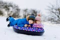 Active toddler girl and school boy sliding together down the hill on snow tube. Happy children, siblings having fun Royalty Free Stock Photo