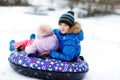 Active toddler girl and school boy sliding together down the hill on snow tube. Happy children, siblings having fun Royalty Free Stock Photo