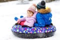 Active toddler girl and school boy sliding together down the hill on snow tube. Happy children, siblings having fun Royalty Free Stock Photo