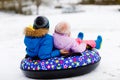 Active toddler girl and school boy sliding together down the hill on snow tube. Happy children, siblings having fun Royalty Free Stock Photo