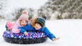 Active toddler girl and school boy sliding together down the hill on snow tube. Happy children, siblings having fun Royalty Free Stock Photo