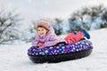 Active toddler girl sliding down the hill on snow tube. Cute little happy child having fun outdoors in winter on sledge Royalty Free Stock Photo