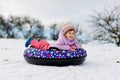 Active toddler girl sliding down the hill on snow tube. Cute little happy child having fun outdoors in winter on sledge Royalty Free Stock Photo