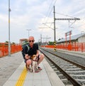 Active tourist with backpack using phone and waiting for train. Man and beagle dog waiting on railway station. Older Royalty Free Stock Photo