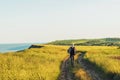 Active tourist, a man with a briefcase in nature, a hipster in a cap is walking along a path on a green hill, healthy lifestyle