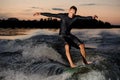 Active wakesurfer in black swimsuit jumping on a wake board at the summer evening Royalty Free Stock Photo