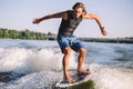 Active wakesurfer jumping on wake board down the river waves. Surfer on wave. Male athlete training on wakesurf training