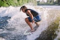 Active wakesurfer jumping on wake board down the river waves. Surfer on wave. Male athlete training on wakesurf training. Active