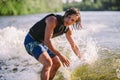 Active wakesurfer jumping on wake board down the river waves. Surfer on wave. Male athlete training on wakesurf training. Active