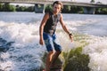 Active Wakesurfer Jumping On Wake Board Down The River Waves. Surfer On Wave. Male Athlete Training On Wakesurf Training. Active