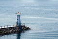 An active white pile beacon painted with Dolhin picture on the rock breakwater near shore in Geoje Island