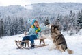 Active winter outdoors games for kids with dog. Happy Christmas vacation concept. Boy enjoying winter, playing with Royalty Free Stock Photo