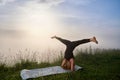 Active woman standing on head and splitting legs on nature