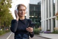 Active woman enjoying music on headphones outdoors in the city