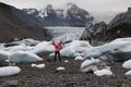 Active Woman jumping in bright red raincoat near the Glacier Lagoon