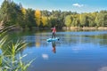 Active woman paddling SUP board on beautiful lake, autumn forest landscape, stand up paddling water adventure Royalty Free Stock Photo