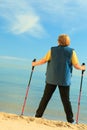 Active woman senior nordic walking on a beach. from behind Royalty Free Stock Photo