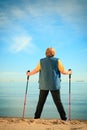 Active woman senior nordic walking on a beach. from behind Royalty Free Stock Photo