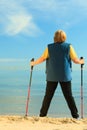 Active woman senior nordic walking on a beach. from behind Royalty Free Stock Photo