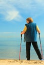 Active woman senior nordic walking on a beach. from behind Royalty Free Stock Photo