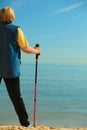 Active woman senior nordic walking on a beach. from behind Royalty Free Stock Photo