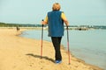 Active woman senior nordic walking on a beach. from behind Royalty Free Stock Photo