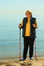 Active woman senior nordic walking on a beach