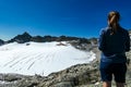 An active woman standing on a rock with view on the glacier of Hoher Sonnblick in Hohe Tauern in Carinthia, Salzburg, Austria