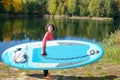 Active woman with SUP board near beautiful lake, nature on background, stand up paddling water adventure Royalty Free Stock Photo