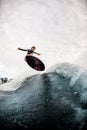 Active woman wake surfer in black wetsuit effectively jumps on surfboard on wave Royalty Free Stock Photo