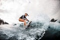 Active woman in wetsuit engaged in extreme sport and rides board on river wave