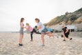 Active women of various ages doing fitness workouts in class exercise with coach on the beach. Ladies working with