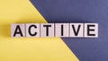 ACTIVE word on wooden cubes on yelloe and gray background