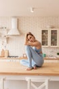 Appealing young lady in light blue outfit sitting in tragic posture