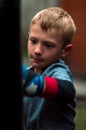 A boy punches a punching bag in blue gloves in the yard Royalty Free Stock Photo