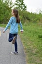Pretty long haired blond girl running down the park path road