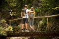 Active young cople hiking on a wooden brifge over mountain creek