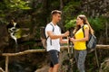 Active young cople hiking on a wooden brifge over mountain creek