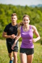 Active young couple running cross country in nature on a fores