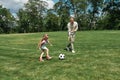 Active young father playing football together with his little daughter on the grass field in the park on a summer day Royalty Free Stock Photo
