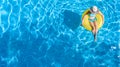 Active young girl in swimming pool aerial top view from above, child relaxes and swims on inflatable ring donut and has fun