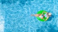 Active young girl in swimming pool aerial top view from above, child relaxes and swims on inflatable ring donut and has fun