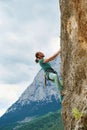 Active young man climbing on height vertical rock with rope. climber looking up and overcoming a difficult route Royalty Free Stock Photo